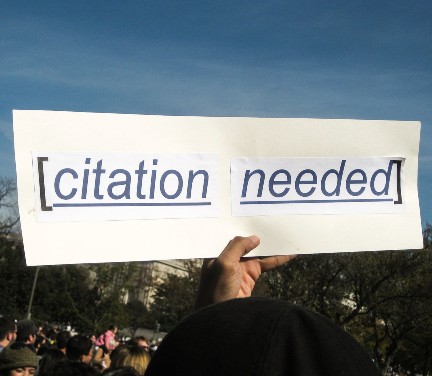 Picture of a hand holding a sign that says [citation needed]